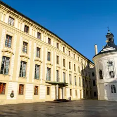 Zamek na Hradczanach, z jego żółtymi fasadami i okrągłą białą kaplicą, lśni w słońcu.
