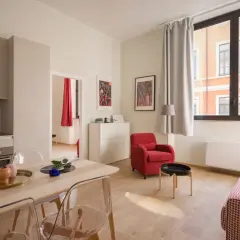 Nowoczesny apartament z kuchnią, jadalnią i salonem. Czy Airbnb jest bezpieczne? Ten przytulny pokój z czerwonym fotelem i kanapą sugeruje, że tak.