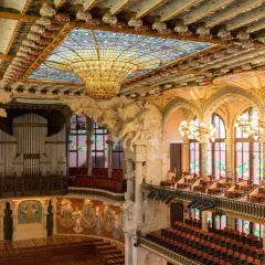 Wnętrze Pałacu Muzyki Katalońskiej z organami, witrażowym sufitem i zdobionymi łukami.