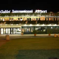 Port lotniczy Piza nocą. Jasny napis "Galilei International Airport" nad wejściem do terminalu.