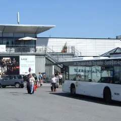 Autobus wahadłowy na lotnisku Sandefjord Torp. Ludzie z bagażami czekają na transport.