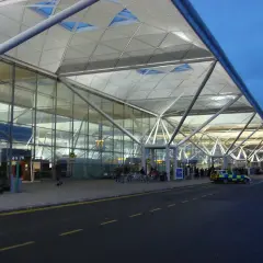 Nowoczesny terminal portu lotniczego Londyn Stansted STN z charakterystycznym dachem i szklanymi fasadami.
