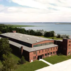 Dawna fabryka samolotów w Mielnie, z ceglanymi budynkami i rozległym terenem nad jeziorem.