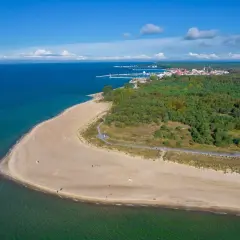 Piękna plaża i las na Helu, z widoczną w oddali zabudową i portem. Warto odwiedzić wieżę obserwacyjną Hel.