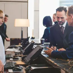 Recepcjonista pyta, czy hotel ma prawo żądać dowodu osobistego. Kobieta i mężczyzna rozmawiają przy ladzie.