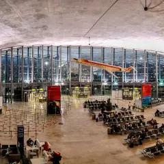 Wnętrze portu lotniczego Walencja z modelem samolotu pod sufitem. Pasażerowie czekają na loty w poczekalni.