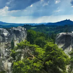 Skaliste formacje w Czeskim Raju w Czechach, otoczone zielonymi lasami, pod burzowym niebem.