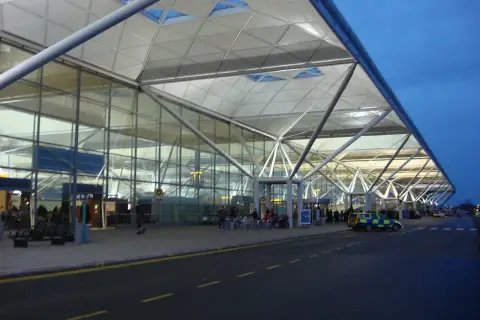 Nowoczesny terminal portu lotniczego Londyn Stansted STN z charakterystycznym dachem i szklanymi fasadami.