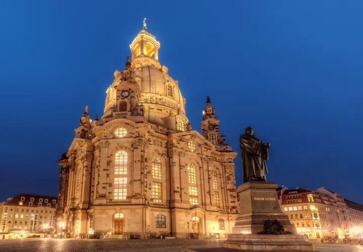 Imponujący kościół Marii Panny w Dreźnie nocą, z pomnikiem Marcina Lutra na pierwszym planie.
