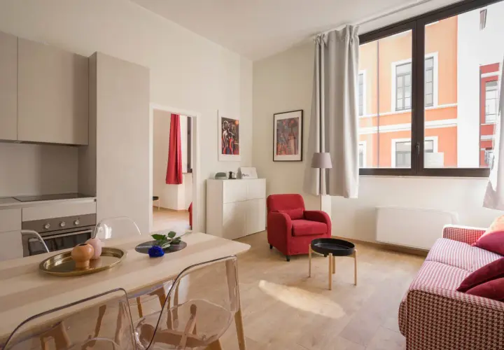 Nowoczesny apartament z kuchnią, jadalnią i salonem. Czy Airbnb jest bezpieczne? Ten przytulny pokój z czerwonym fotelem i kanapą sugeruje, że tak.