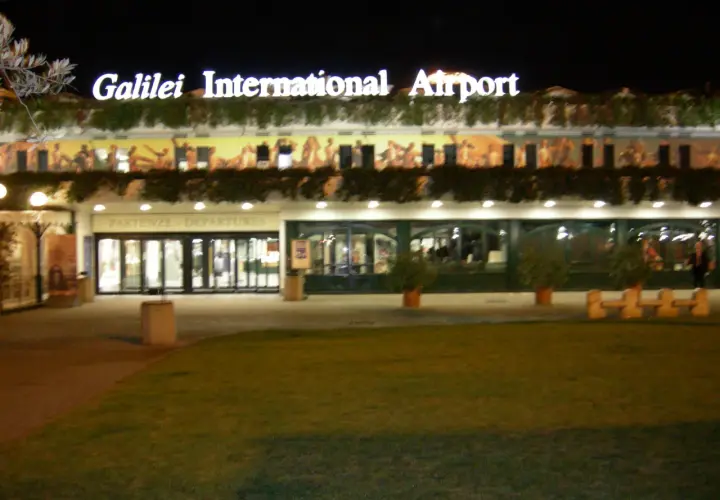 Port lotniczy Piza nocą. Jasny napis "Galilei International Airport" nad wejściem do terminalu.
