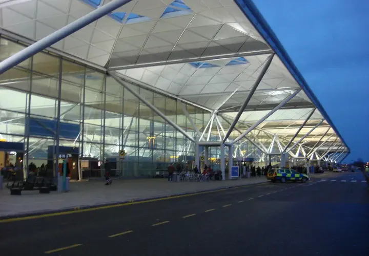 Nowoczesny terminal portu lotniczego Londyn Stansted STN z charakterystycznym dachem i szklanymi fasadami.