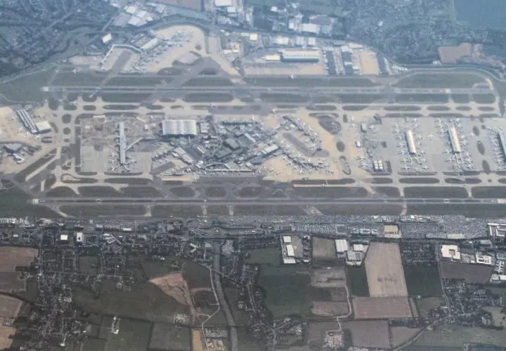 Widok z lotu ptaka na port lotniczy Londyn Heathrow z licznymi samolotami na płycie lotniska i pasami startowymi.