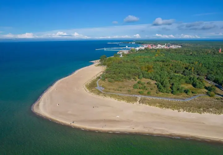 Piękna plaża i las na Helu, z widoczną w oddali zabudową i portem. Warto odwiedzić wieżę obserwacyjną Hel.