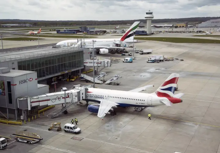 Port lotniczy Londyn Gatwick: samoloty British Airways i Emirates przy rękawach, w tle wieża kontroli lotów.