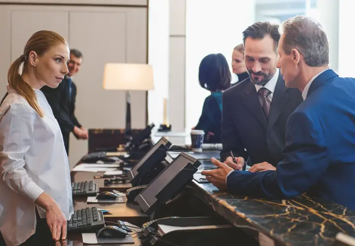 Recepcjonista pyta, czy hotel ma prawo żądać dowodu osobistego. Kobieta i mężczyzna rozmawiają przy ladzie.