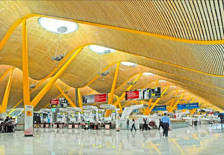 Nowoczesna architektura lotniska Madryt Barajas z charakterystycznym, falującym dachem i żółtymi podporami.