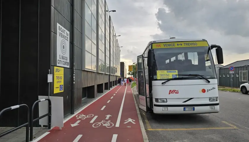 Autobus na lotnisku Treviso z napisem "Venice <-> Treviso". Czerwona ścieżka rowerowa i piesza obok budynku.
