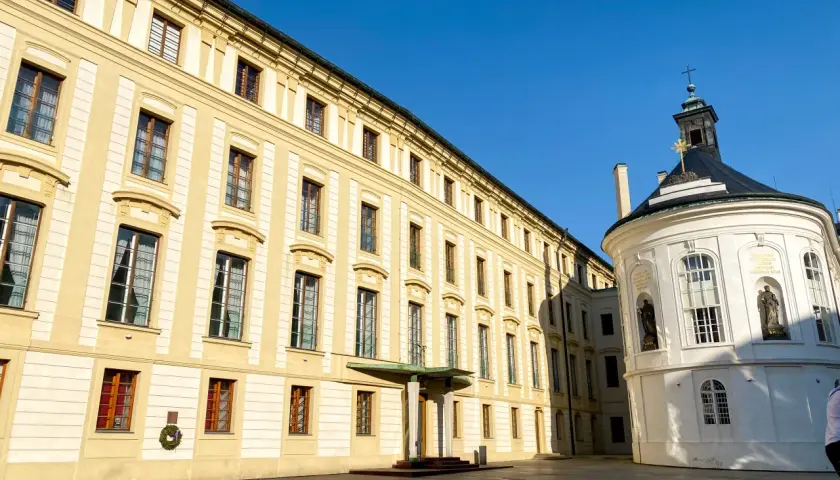 Zamek na Hradczanach, z jego żółtymi fasadami i okrągłą białą kaplicą, lśni w słońcu.