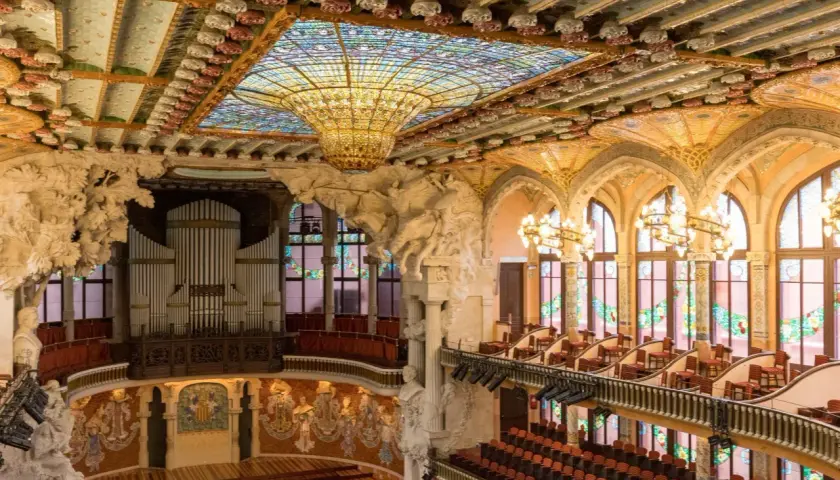 Wnętrze Pałacu Muzyki Katalońskiej z organami, witrażowym sufitem i zdobionymi łukami.