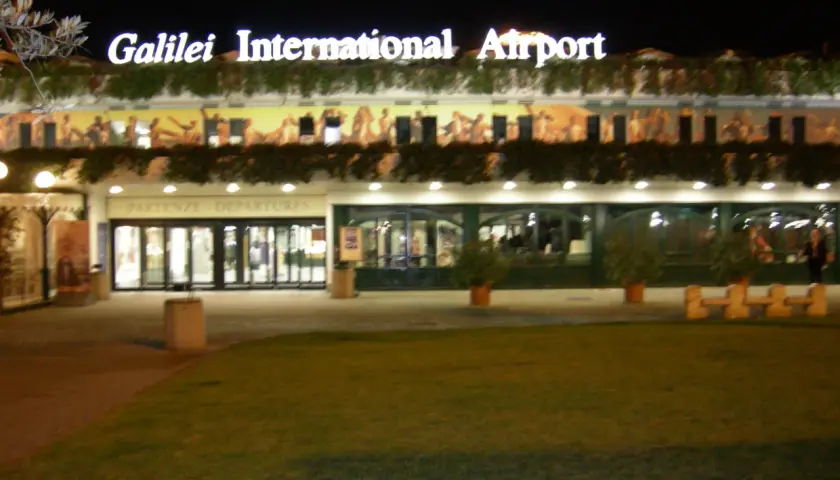 Port lotniczy Piza nocą. Jasny napis "Galilei International Airport" nad wejściem do terminalu.