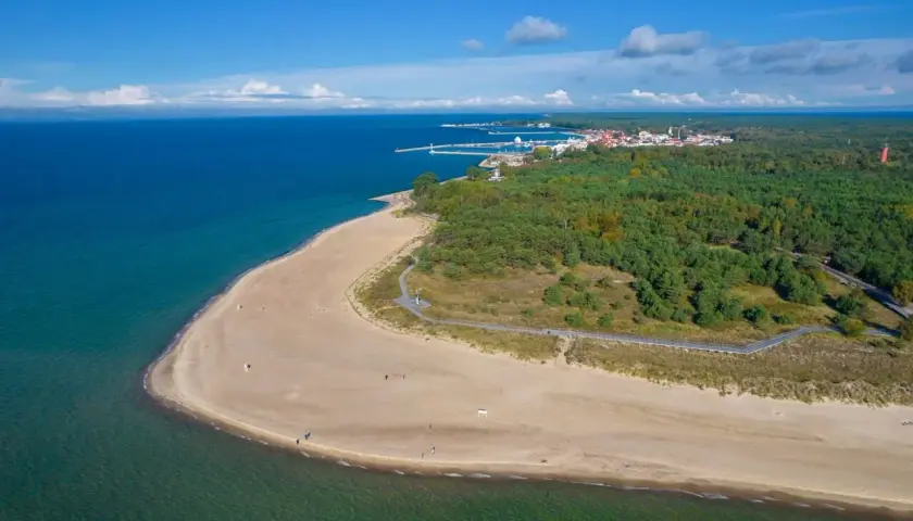 Piękna plaża i las na Helu, z widoczną w oddali zabudową i portem. Warto odwiedzić wieżę obserwacyjną Hel.