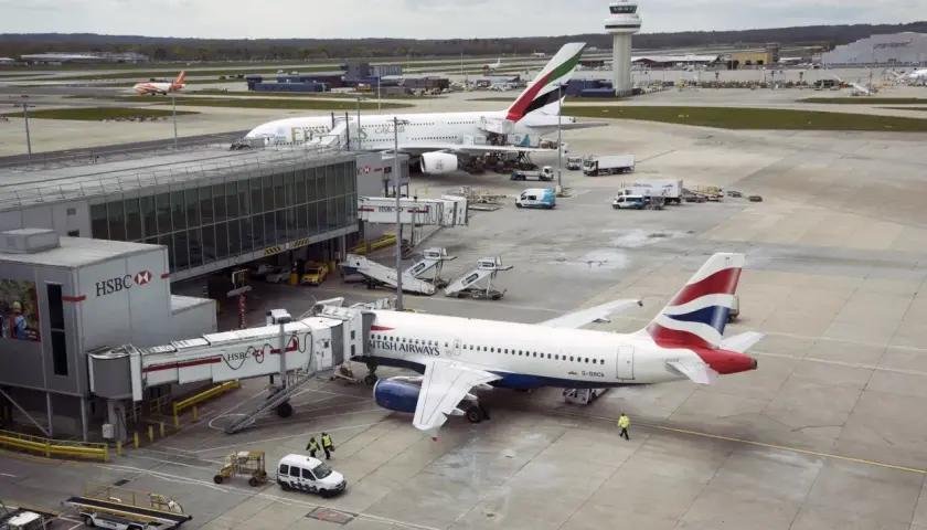 Port lotniczy Londyn Gatwick: samoloty British Airways i Emirates przy rękawach, w tle wieża kontroli lotów.