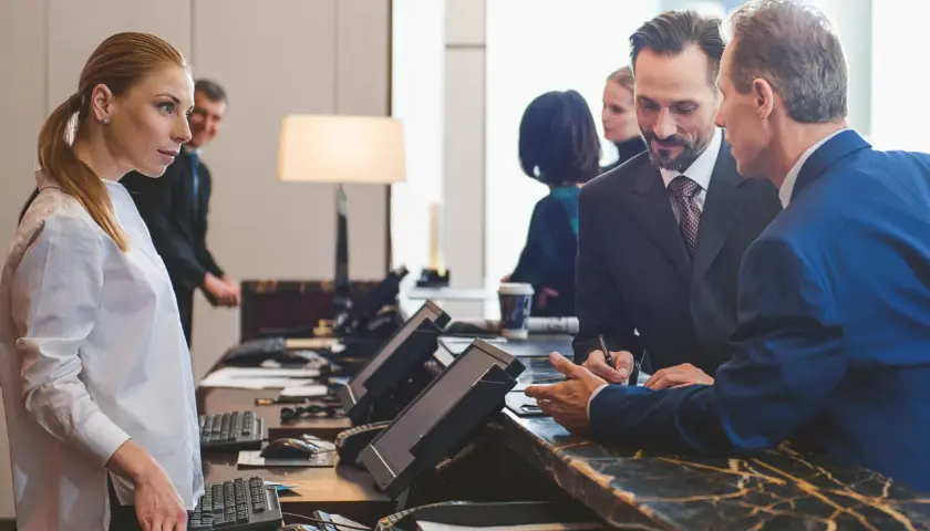 Recepcjonista pyta, czy hotel ma prawo żądać dowodu osobistego. Kobieta i mężczyzna rozmawiają przy ladzie.