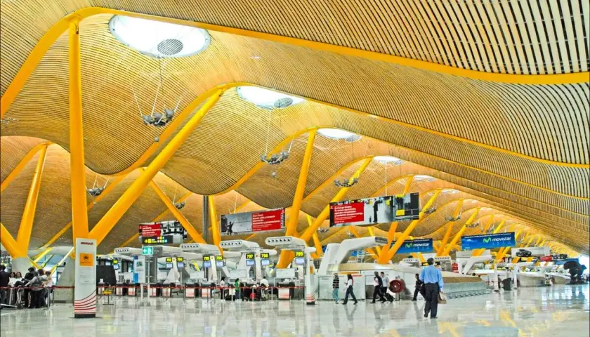 Nowoczesna architektura lotniska Madryt Barajas z charakterystycznym, falującym dachem i żółtymi podporami.