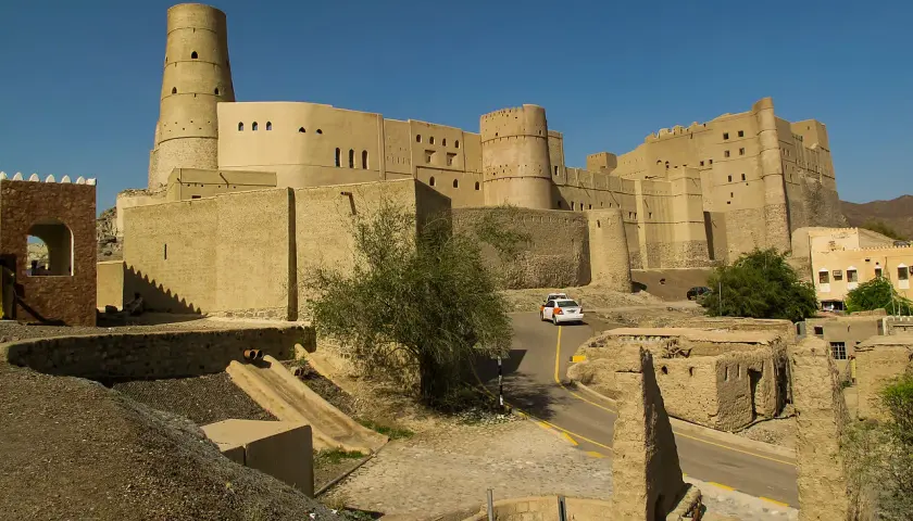 Imponujący fort Bahla w Omanie, z charakterystyczną okrągłą wieżą, góruje nad krajobrazem.
