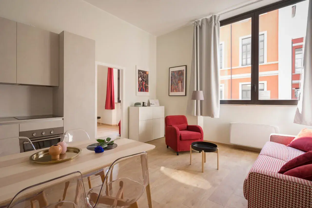 Nowoczesny apartament z kuchnią, jadalnią i salonem. Czy Airbnb jest bezpieczne? Ten przytulny pokój z czerwonym fotelem i kanapą sugeruje, że tak.