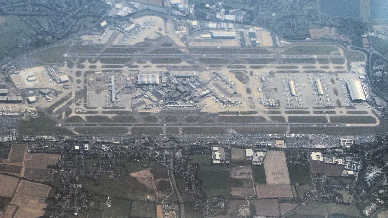 Widok z lotu ptaka na port lotniczy Londyn Heathrow z licznymi samolotami na płycie lotniska i pasami startowymi.