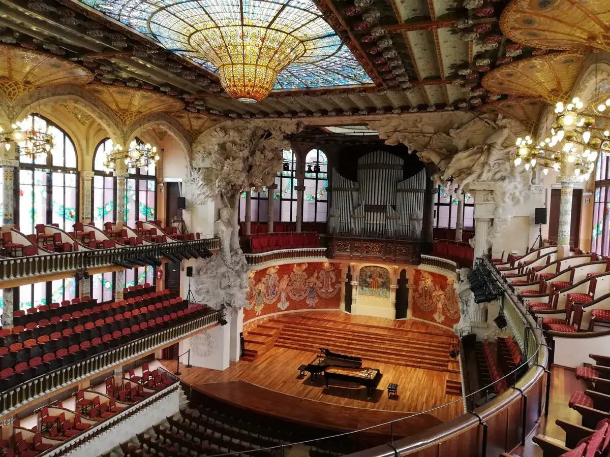 Wnętrze Pałacu Muzyki Katalońskiej z organami, fortepianem i zdobionym sufitem.