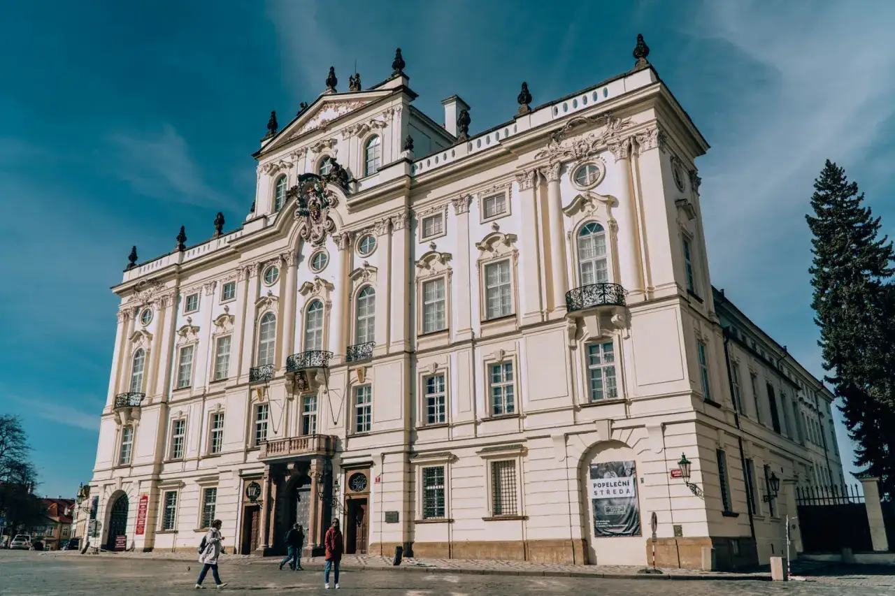Elegancki zamek na Hradczanach, z bogato zdobioną fasadą i balkonami, na tle błękitnego nieba.