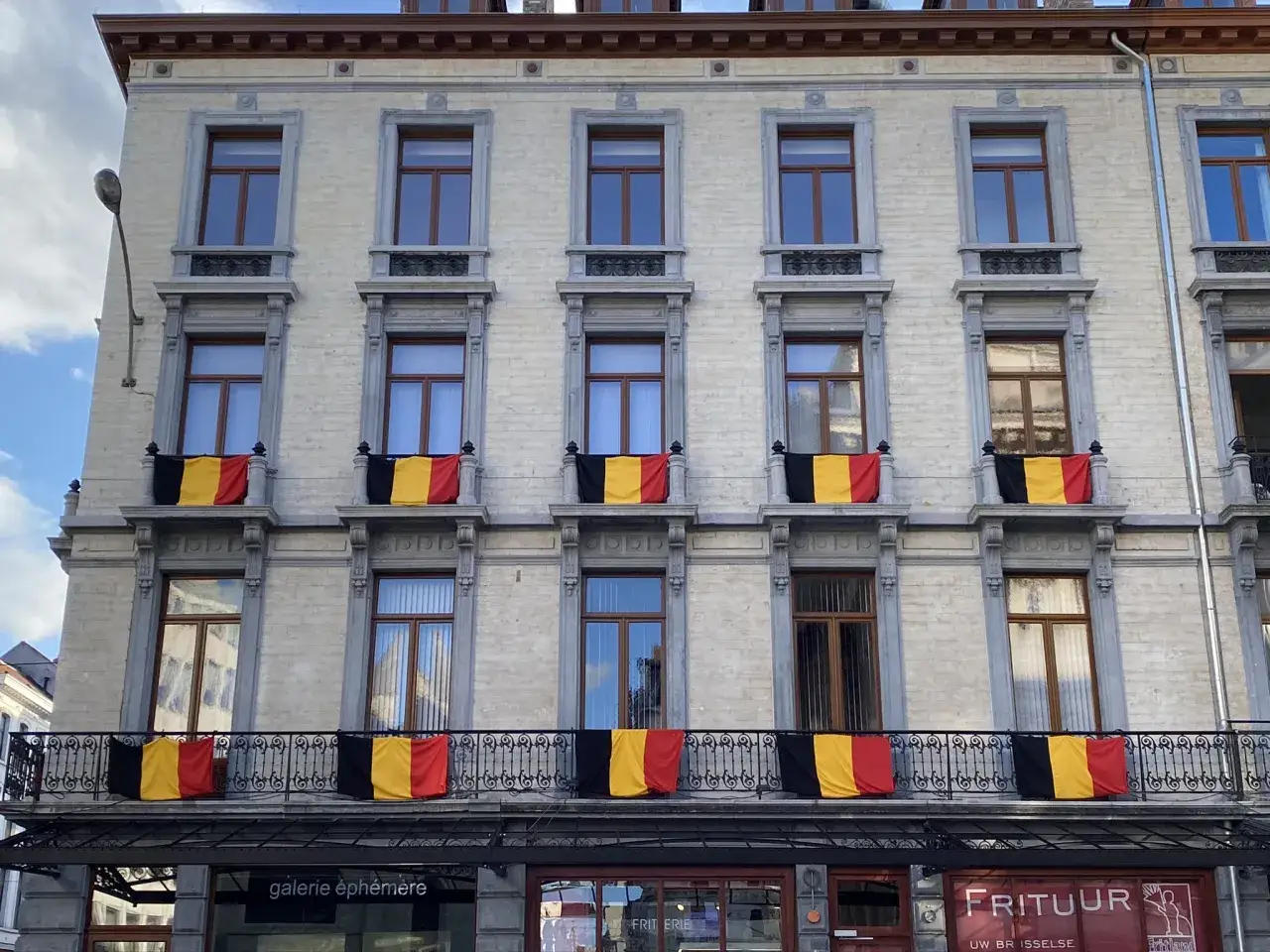 Belgijskie flagi zdobią fasadę kamienicy, zapraszając do odkrywania uroków Brukseli. Co zobaczyć w tym mieście?