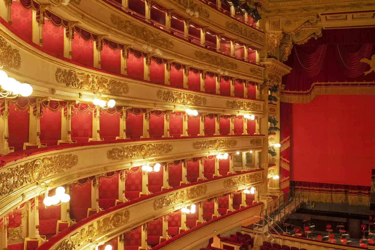 Wnętrze La Scala w Mediolanie: złote zdobienia, czerwone aksamitne loże i kurtyny tworzą atmosferę luksusu.