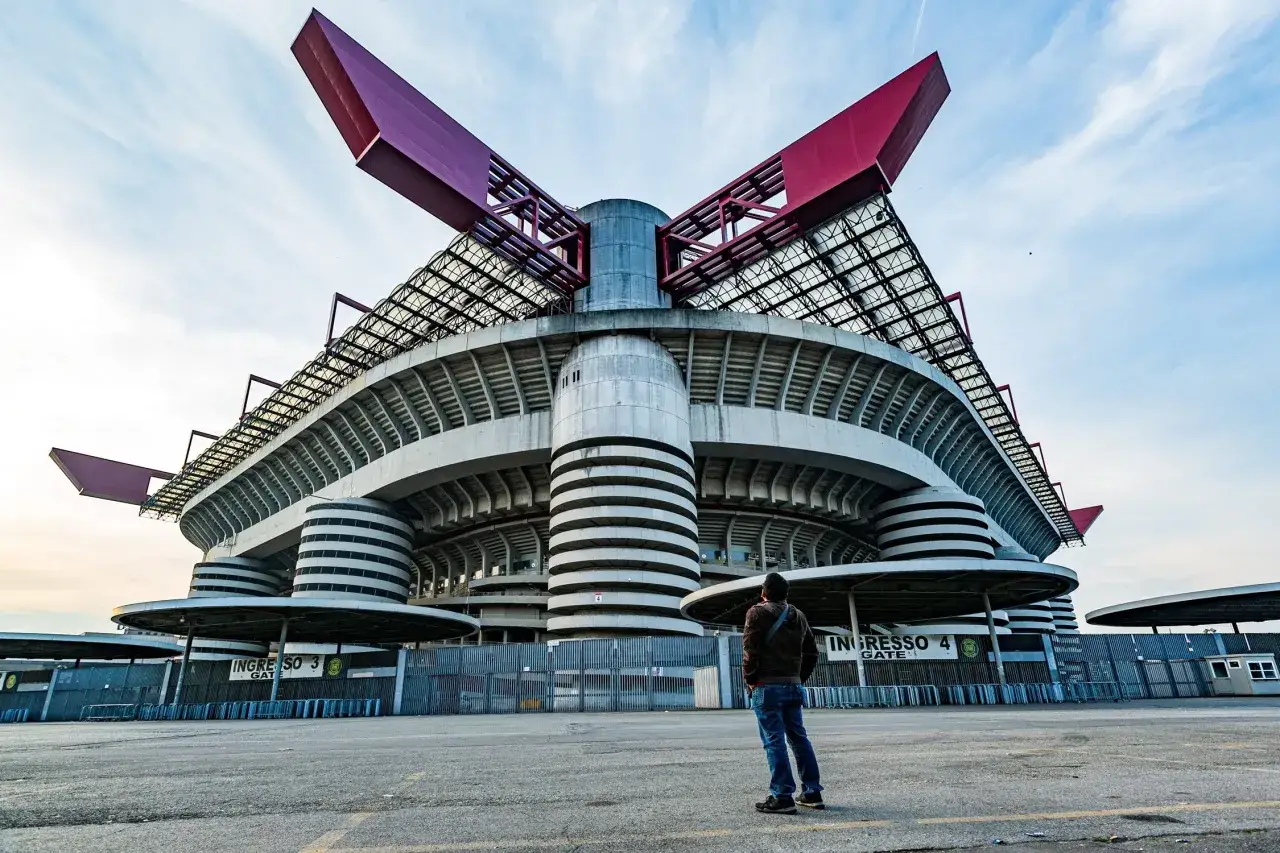 Stadion Interu Mediolan, znany jako San Siro, z charakterystycznymi czerwonymi elementami dachu i betonowymi wieżami.