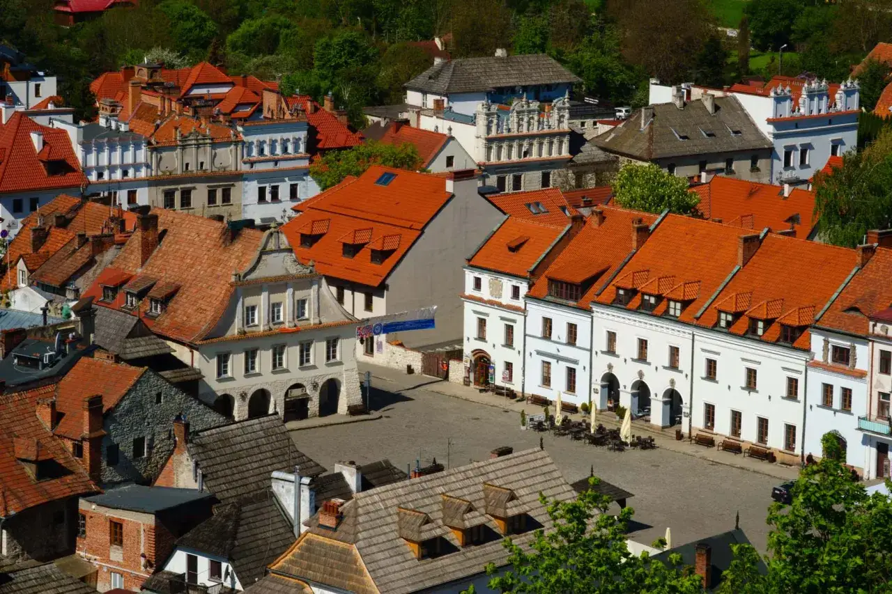 Kazimierz Dolny atrakcje: malowniczy rynek z kamieniczkami o czerwonych dachach, urokliwe uliczki i zieleń.