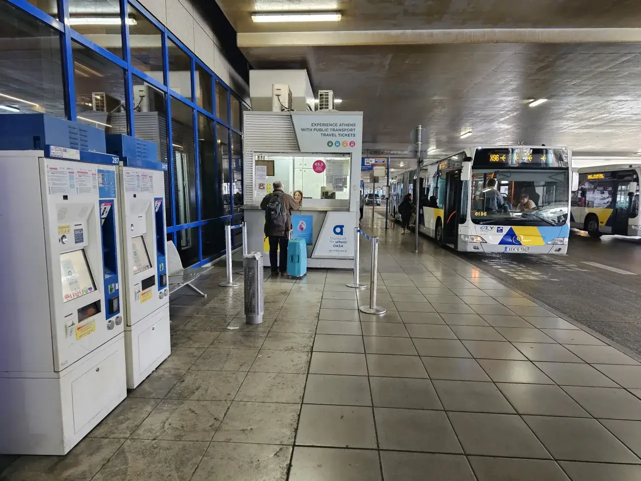 Port lotniczy Ateny: automaty biletowe, punkt obsługi pasażera i autobusy czekające na pasażerów.