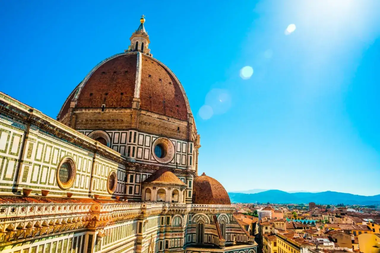 Majestatyczna katedra Santa Maria del Fiore we Florencji, z jej charakterystyczną kopułą, góruje nad miastem w słoneczny dzień.