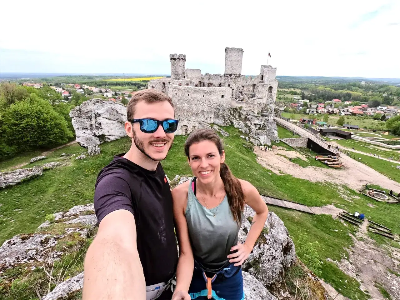 Para co zobaczyć w Zawierciu? Ruiny zamku Ogrodzieniec na skale, z parą turystów na pierwszym planie.