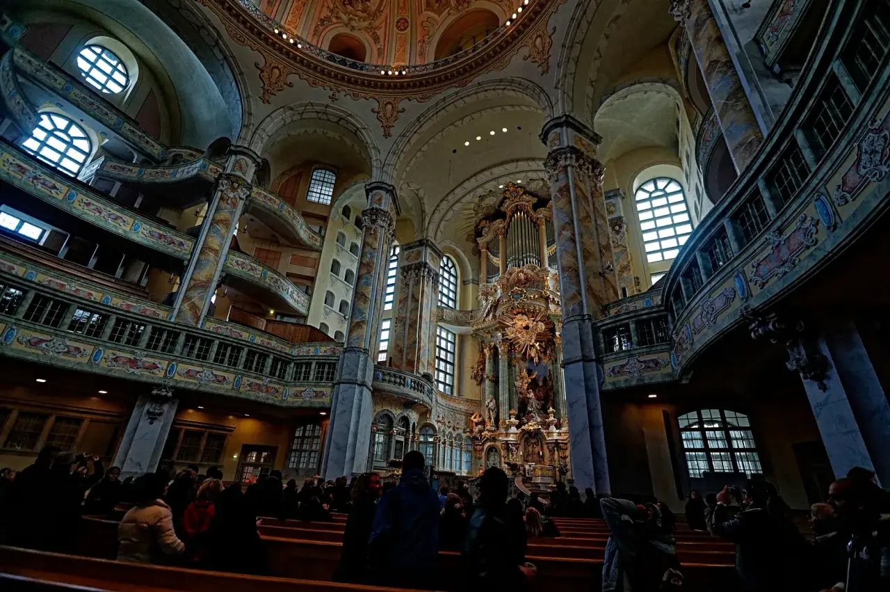 Wnętrze kościoła Marii Panny w Dreźnie, z widocznymi organami, galeriami i wiernymi siedzącymi w ławkach.