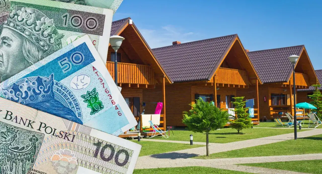 Polskie banknoty na tle domków letniskowych. Zastanawiasz się, gdzie najlepiej rezerwować noclegi, by było tanio i wygodnie?