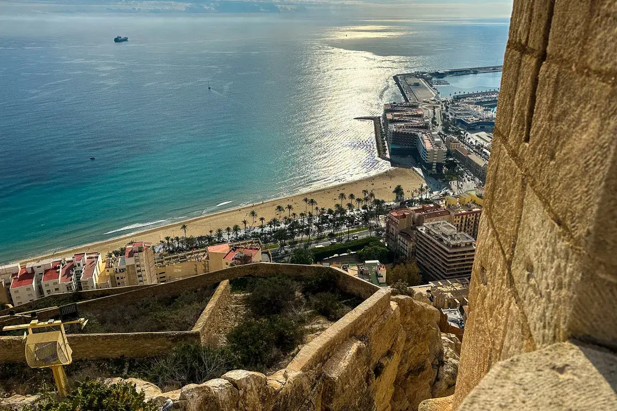 Widok z zamku na plażę i port w Alicante. Słoneczna plaża, turkusowe morze i miasto – to wszystko, co warto zobaczyć w Alicante.