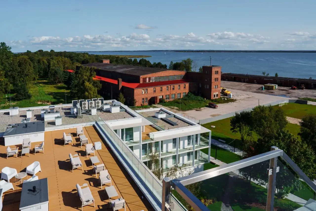 Dawna fabryka samolotów w Mielnie, dziś otoczona zielenią i nowoczesną architekturą, z widokiem na jezioro.