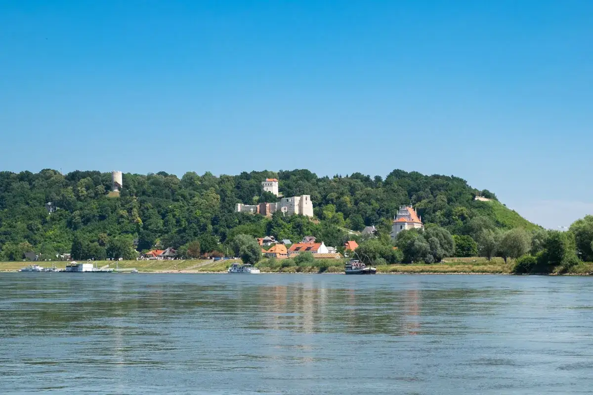 Widok na wzgórze z ruinami zamku i wieżą, a u podnóża miasteczko. Kazimierz Dolny atrakcje zachwycają o każdej porze roku.