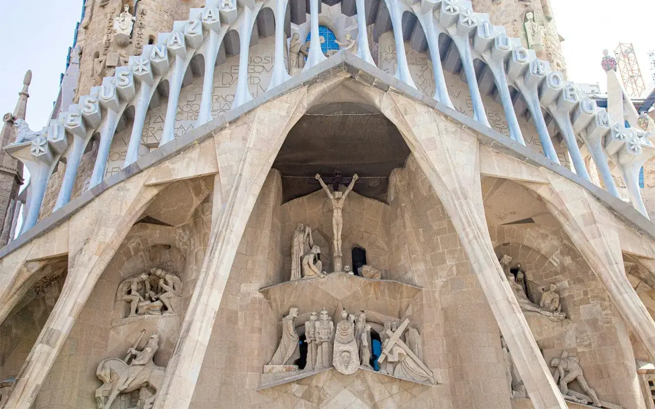 Kamienna fasada La Sagrada Familia z rzeźbami przedstawiającymi sceny biblijne, w tym ukrzyżowanie Jezusa.