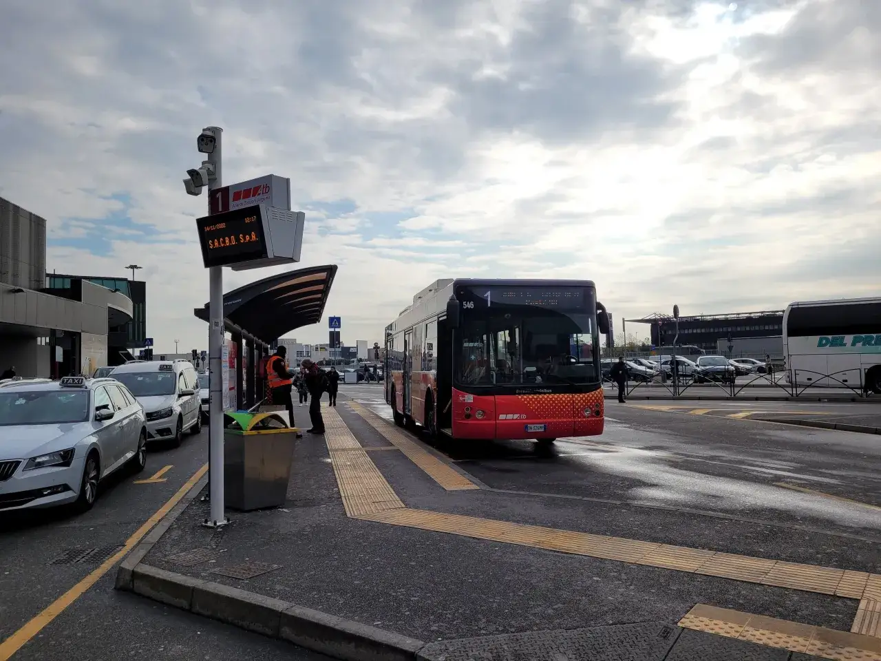 Autobus linii 1 na przystanku lotnisko Mediolan Bergamo. W tle taksówki i budynek terminala.