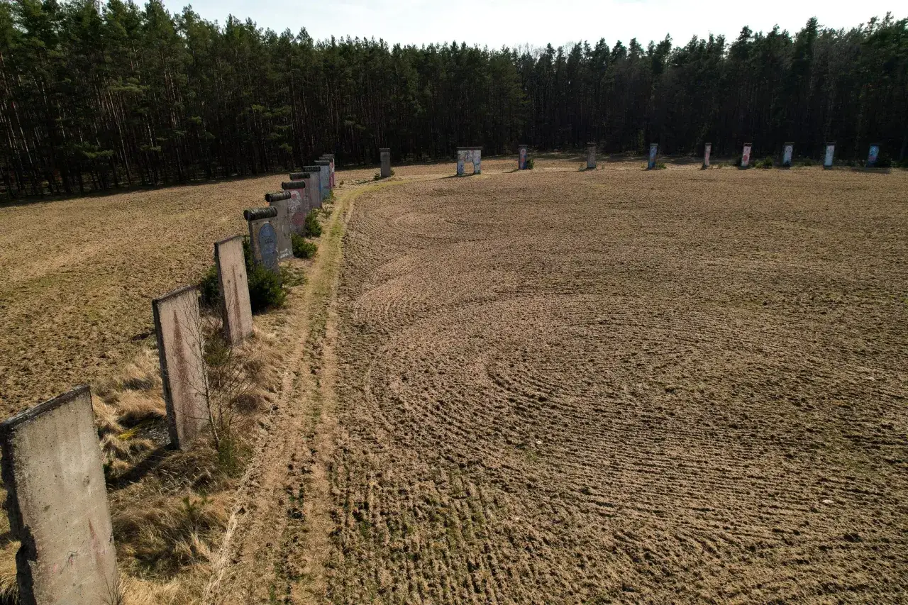 Fragment muru berlińskiego w lesie, z malowanymi panelami, przypomina o historii.
