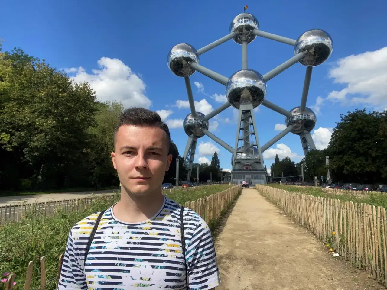 Młody mężczyzna przed Atomium, jednym z głównych miejsc, które warto zobaczyć w Brukseli.